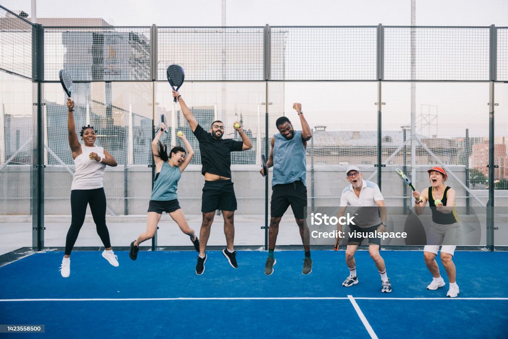 Group photo after successful paddle tennis match Mixed race group of people on rooftop paddle tennis court. Padel Stock Photo