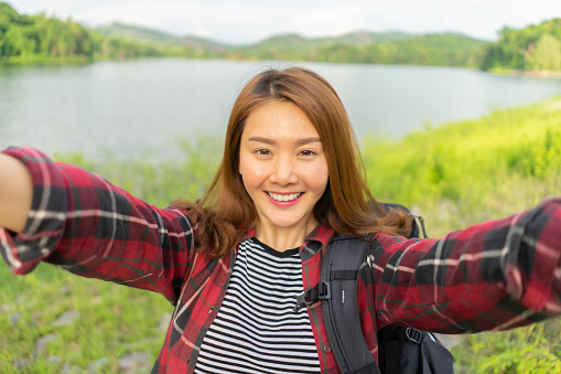 Travel Vacationing Tourist Selfie,Asian Woman taking self-portrait photo in lake forest with smartphone, Young Girl on summer vacation visiting famous tourists destination have fun smiling to camera