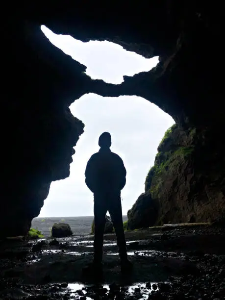 Silhouete teenage boy standing in Joda's Cave Hjörleifshöf∂i Southern Iceland