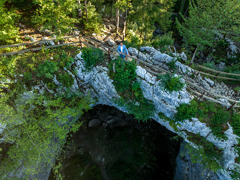 Aerial View Of A Businessman Standing On Top Of A Stunning Natural Bridge Formation