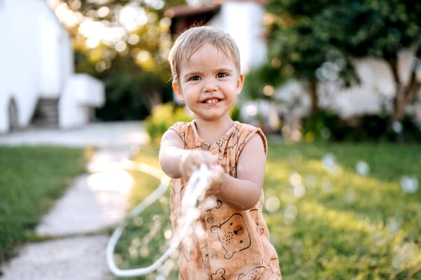 istock Cute little smiling boy playing with garden hose 1423560924
