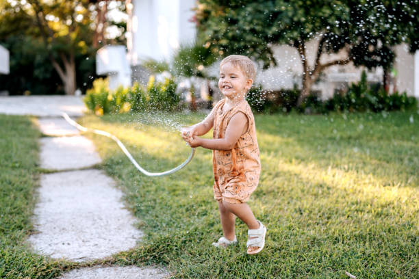 istock Cute little smiling boy playing with garden hose 1423560927