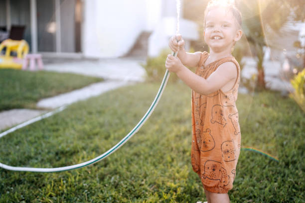 istock Cute little smiling boy playing with garden hose 1423561124