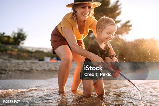 istock Mother and cute little toddler playing with fishing toy on the sea 1423561474
