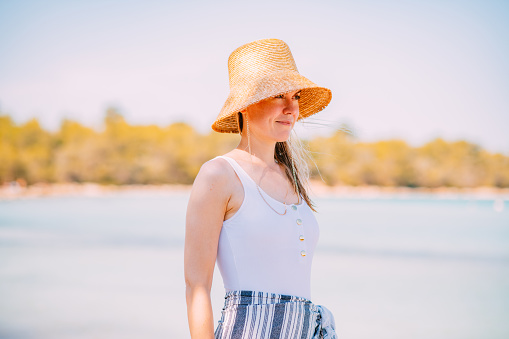 Caucasian Blonde Woman in Straw Hat at the Beach