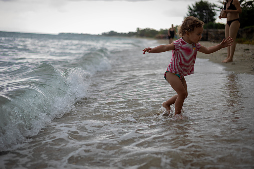 The little girl is playing on the seashore.