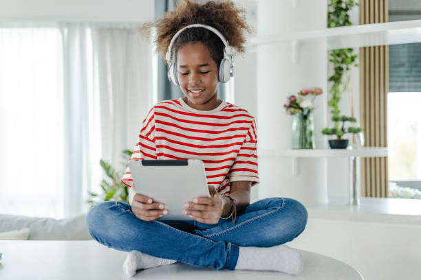 istock Cute girl is using digital tablet at home mid school 1423562940