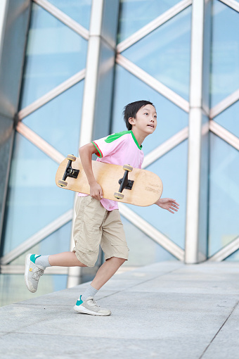 Asian teenage boy skateboarding outdoors