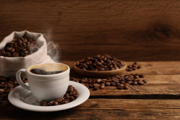 istock Cup of aromatic hot coffee and beans on wooden table, space for text 1423565198