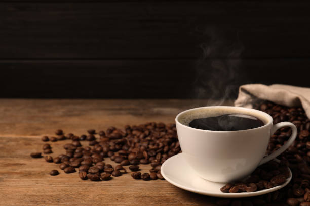 istock Cup of aromatic hot coffee and beans on wooden table. Space for text 1423565214