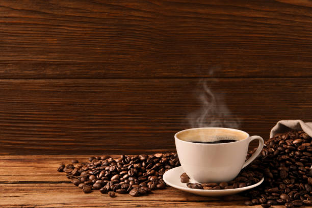 istock Cup of aromatic hot coffee and beans on wooden table, space for text 1423565238