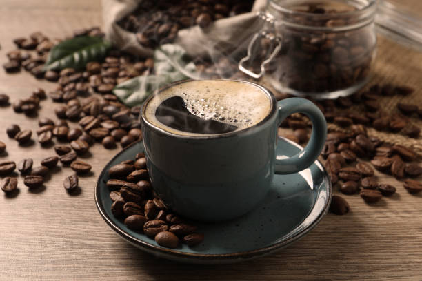 istock Cup of aromatic hot coffee and beans on wooden table 1423565245