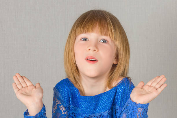 портрет маленькой девочки, одетой в синее платье на сером фоне. - kinder surprise стоковые фото и изображения