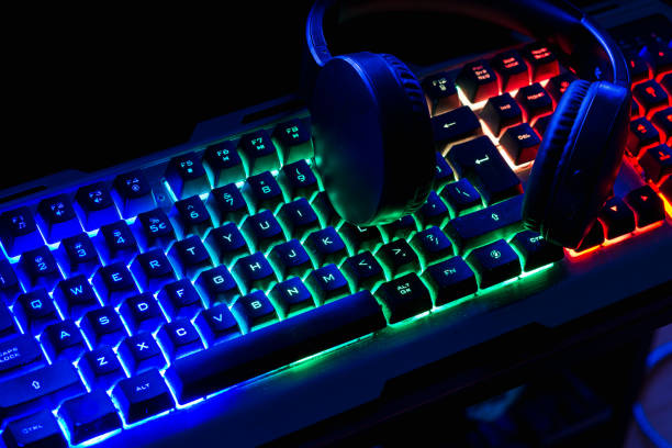 istock Pro gaming illuminated desk, headset, keyboard, computer neon lights. Cyber sport equipment laying on desktop, ready for online video gaming.Dark shot. 1423568908