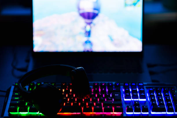istock Gamer workspace concept.Gaming gear, keyboard, laptop, Headset illuminated background with RGB Color.Dark shot. 1423568948