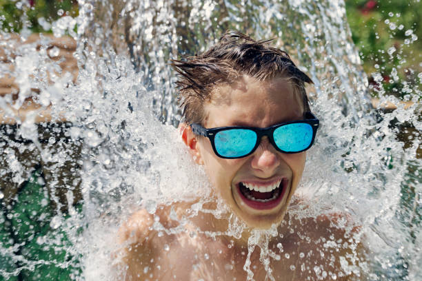 istock Teenage boy enjoying being splashed in waterpark 1423571099