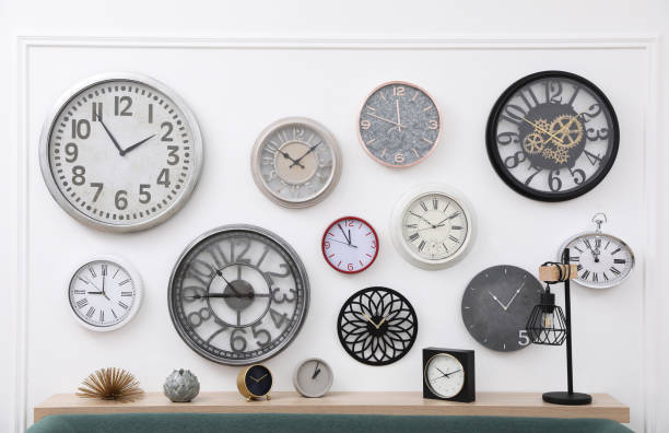 istock Collection of different clocks on white wall in room 1423571301