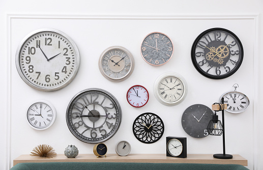 Collection of different clocks on white wall in room