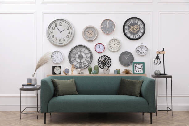 istock Collection of different clocks and comfortable sofa in stylish room. Interior design 1423571302