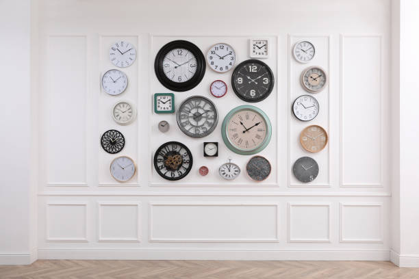 istock Collection of different clocks hanging on white wall in room 1423571305