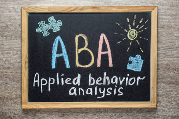 small blackboard with text aba applied behavior analysis and drawings on wooden table, top view - behavioral problems imagens e fotografias de stock