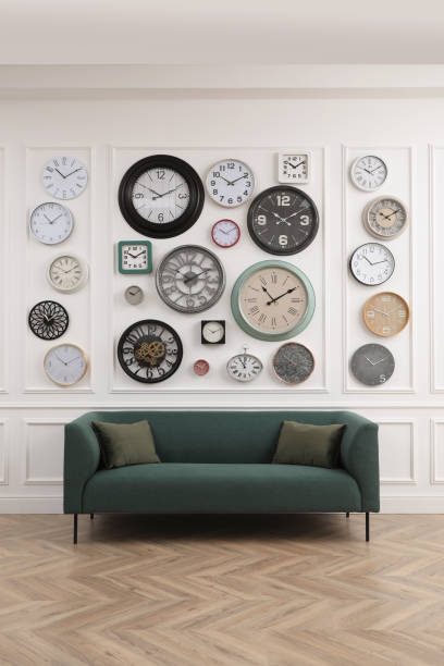 istock Collection of different clocks and comfortable sofa in stylish room. Interior design 1423571592