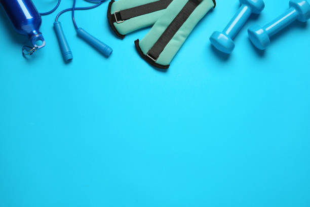 istock Turquoise ankle weights and sport equipment on light blue background, flat lay. Space for text 1423573726