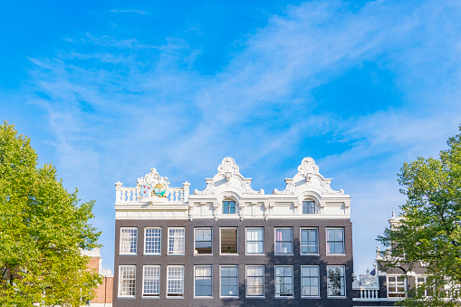 Amsterdam canal house facades at the Keizersgracht  in the Western part of the canal district with a blue sky in the background during summer.