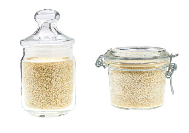 istock Glass jar with white sesame seeds isolated on a white background. 1423574041