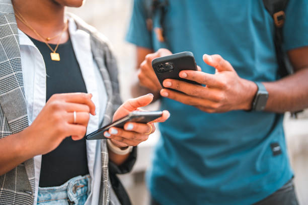 Handsome Young Black Couple Using Smart Phones While Hanging Out In The City stock photo