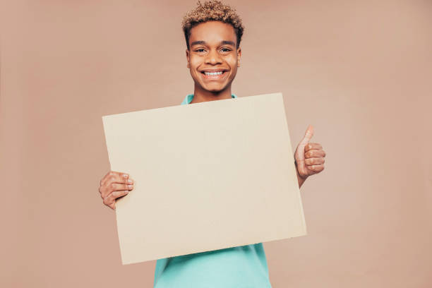 istock Latin american boy holding advertising banner at studio 1423578594