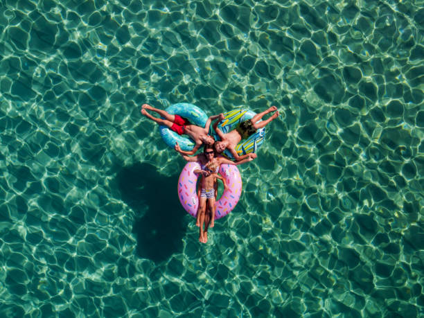 imagen con dron de personas, flotando en anillos inflables de colores en el mar - pleasant bay fotografías e imágenes de stock