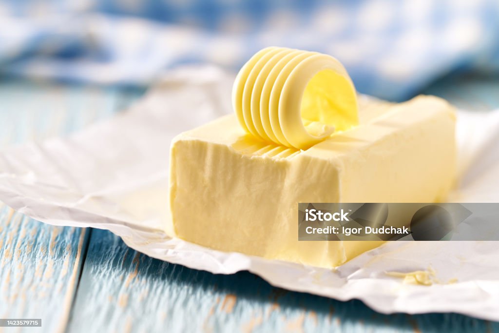 whole block butter on a blue wooden table, selective focus. piece of butter on a blue wooden table, selective focus. Butter Stock Photo