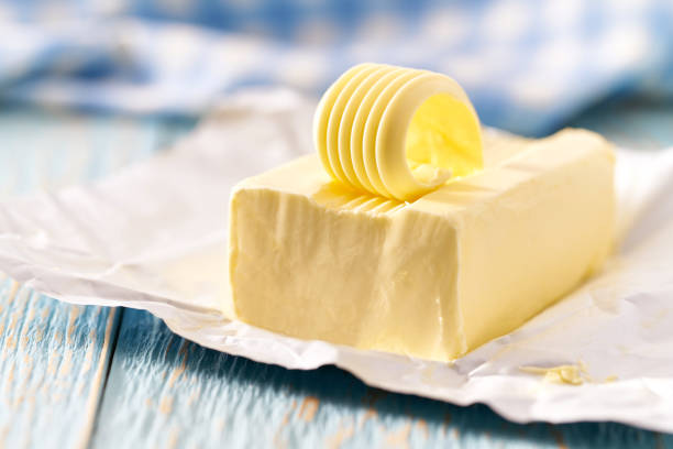 whole block butter on a blue wooden table, selective focus. - margarine dairy product butter close up imagens e fotografias de stock