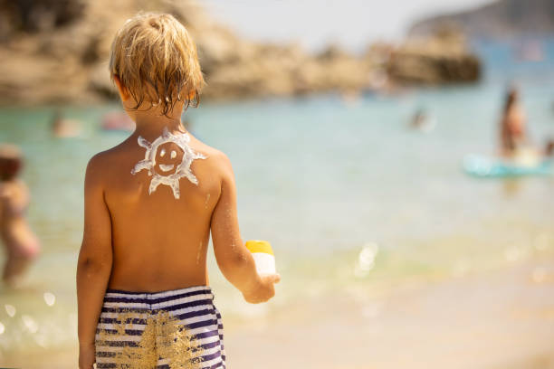 istock Happy child, blond boy on the beach with applied sun screen,  enjoying summer, playing 1423579810