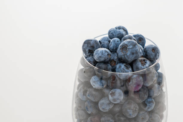 istock Glass bowl with blueberries on white table, close up 1423580306