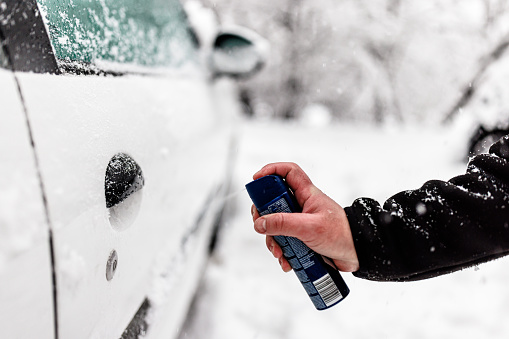 Man has Problems with a Car Door During a Winter Day and Trying to Unfreeze the Lock with a Spray.