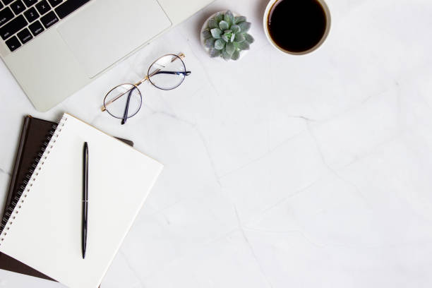 istock Working space with computer, glasses, coffee, notebook and cactus over the marble background. 1423582834