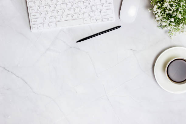 istock Computer, coffee, pen and flowers over the marble background. 1423582869