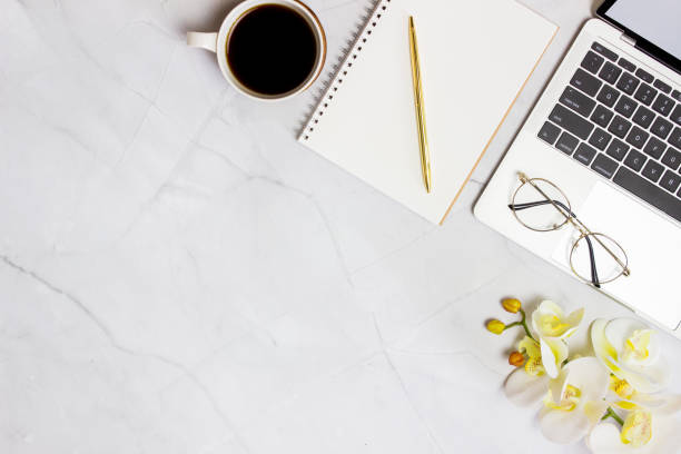 istock Working space with computer, glasses, coffee, notebook and orchid over the marble background. 1423582918