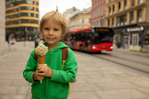Toddler child in the center of Oslo, capital of Norway, eating ice cream summertime