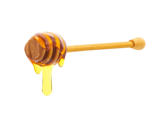 istock Honey dripping from honey dipper isolated on white background. 1423583933
