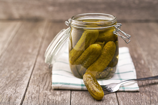 Pickles in jar. Tasty marinated cucumbers in jar on a wooden table, selective focus.