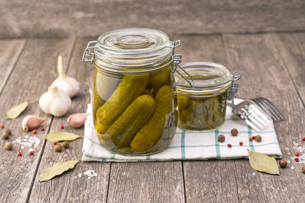 istock Pickled cucumbers with herbs and spices, on a wooden table, selective focus. 1423585778