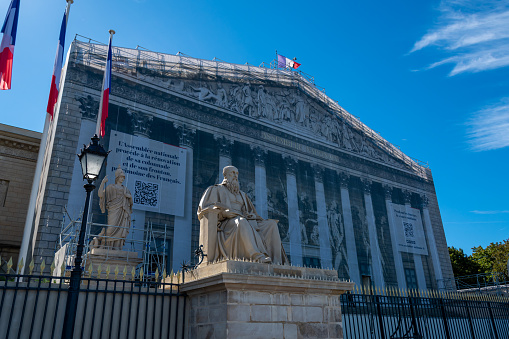 Exterior view of the main facade of the French National Assembly with netting covering the scaffolding of the colonnade and pediment restoration works, Paris, France