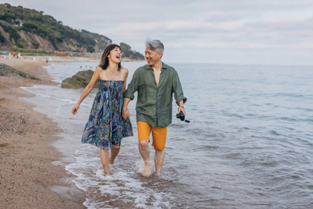 아름 다운 햇빛 나는 해변에 산책 하는 행복 한 매력적인 커플 - middle human age couple women 뉴스 사진 이미지