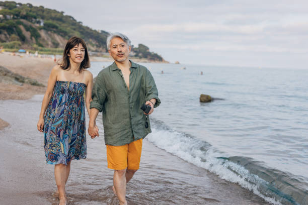 feliz pareja atractiva caminando por la playa soleada - couple walking old middle fotografías e imágenes de stock