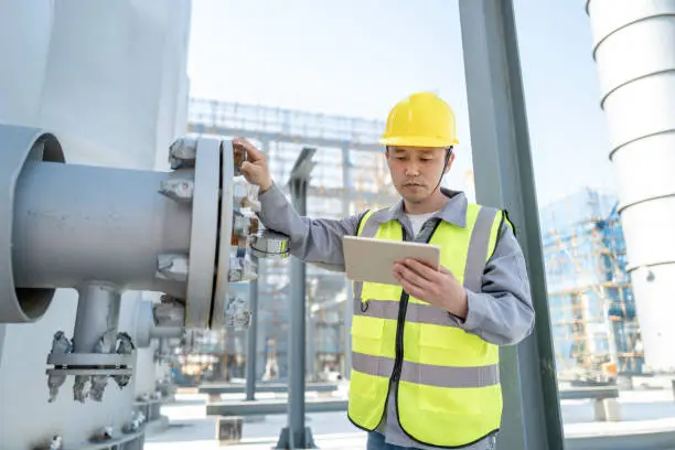 Photo of A male engineer was checking equipment in a chemical plant with a tablet computer