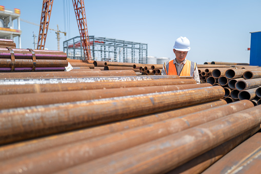 A male worker took a tablet computer to check the quality of steel pipes