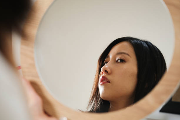 istock Young woman looking at mirror 1423593567